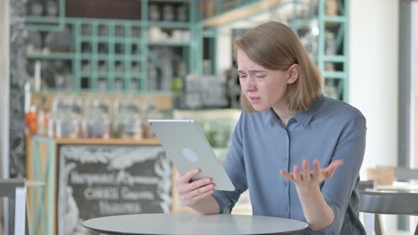 Young Woman Reacting to Loss on Tablet in Cafe