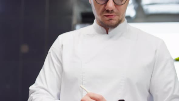 Chef Taking Notes and Talking with Colleague in Restaurant Kitchen