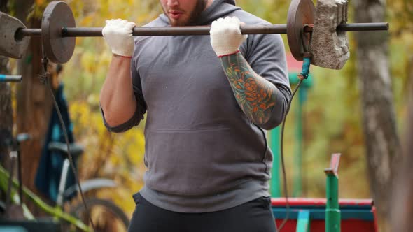 A Man Bodybuilder Pumping His Hands with the Dumbbells Made of Bricks and Weights - Training on the