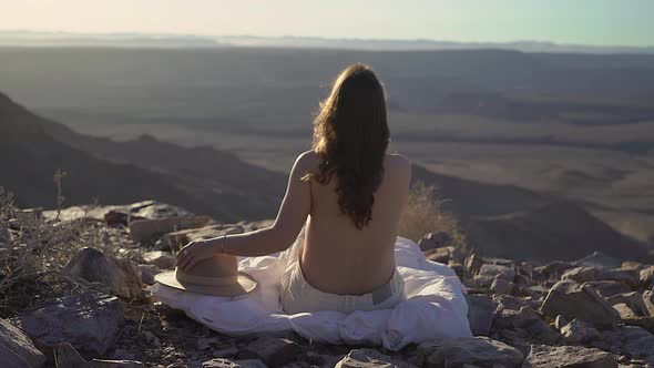 Young Woman Sitting Topless on Blanket at Edge of Fish River Canyon in Namibia