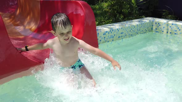 Boy slide on slider in water park on summer holiday.  Happy boy sliding down the water slide.
