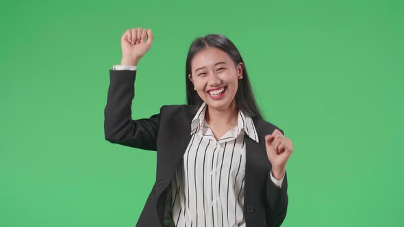 A Smiling Asian Business Woman Dancing While Standing On Green Screen Background In The Studio