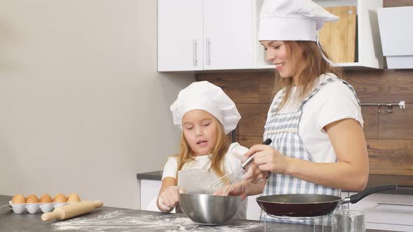 Woman and Cute Daughter Cooking on Kitchen, Making Dough for Birthday Party