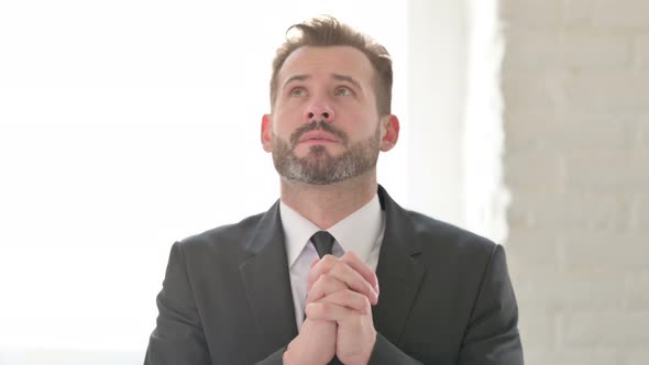 Middle Aged Businessman Praying with Fingers Crossed