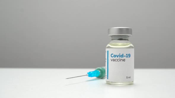Close up panning of a COVID-19 vaccine bottle and a syringe for injection