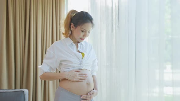 Asian young beautiful pregnancy woman holding and stroking her tummy.