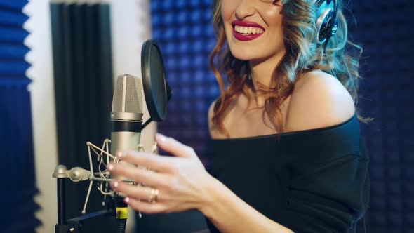 Young woman recording a song in a professional studio. The girl sings into the microphone.