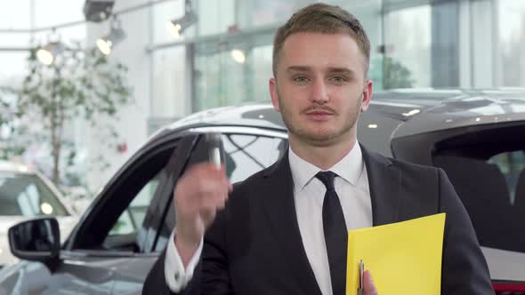 Professional Car Salesman Holding Car Key, Looking To the Camera Confidently