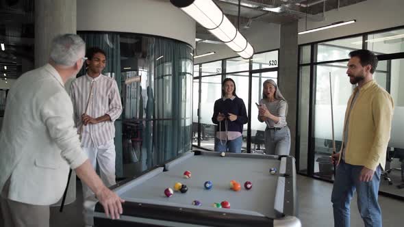 Group of business people playing billiards in office, active rest during break at work.
