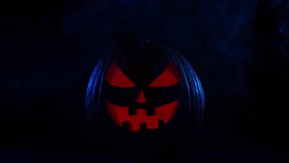 Scary laughing pumpkin and an old skull over the frightening gothic background.