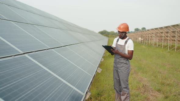 Worker Writing on Clipboard on Solar Station