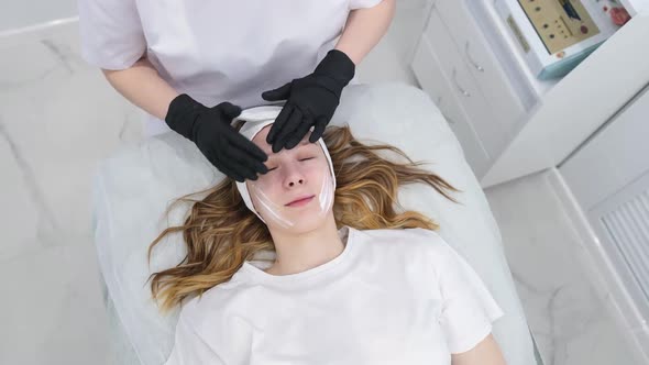 Cosmetologist Applies a Woman a Therapeutic Mask on Her Face