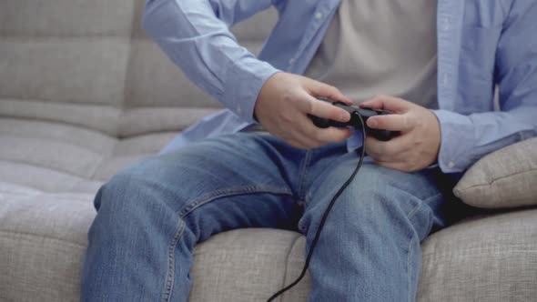 Unrecognizable Young Guy Playing Videogames with Joystick at Home