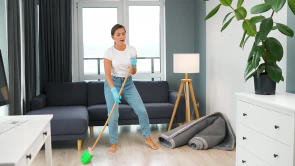 Woman Cleaning the House and Having Fun Dancing with a Broom