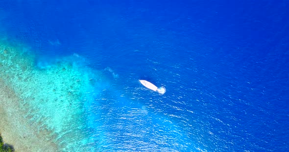 Wide birds eye tourism shot of a paradise sunny white sand beach and aqua blue water background in c