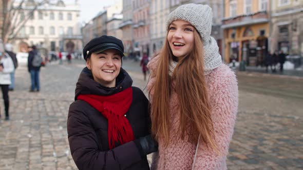 Two Smiling Women Tourists Walking Together on City Street Family Couple Talking Embracing