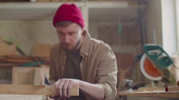 Carpenter Cutting Wooden Plank with Hand Saw