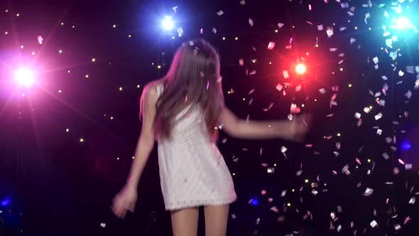 Carefree Girl Dancing and Throws Glitter Confetti Against Disco Lights
