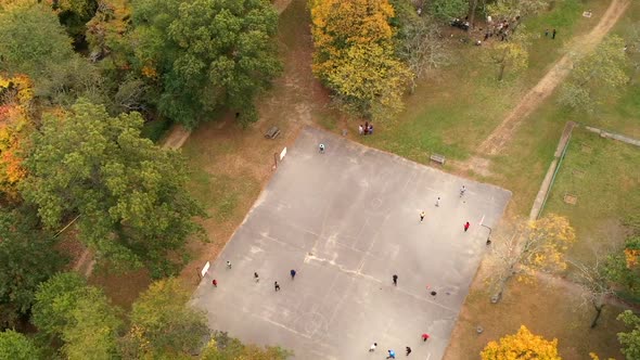 a top down time lapse over a basketball court surrounded by colorful tree tops. It is day time & the