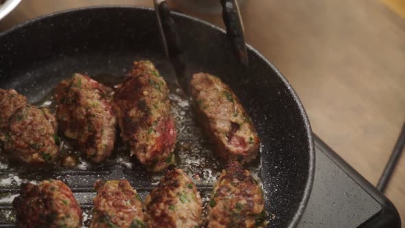 Unrecognizable cook turning Salisbury steaks on pan