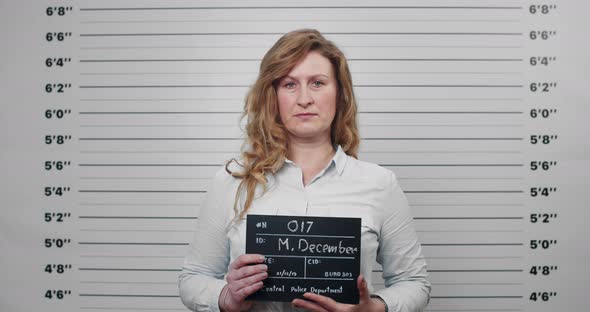 Portrait of Woman in Middle 40s Holding Sign for Photo in Police Department
