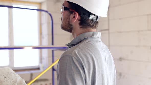 A man builder looks at a construction drawing in a building.