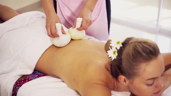 Massage Therapist Using Herbal Compress on Woman