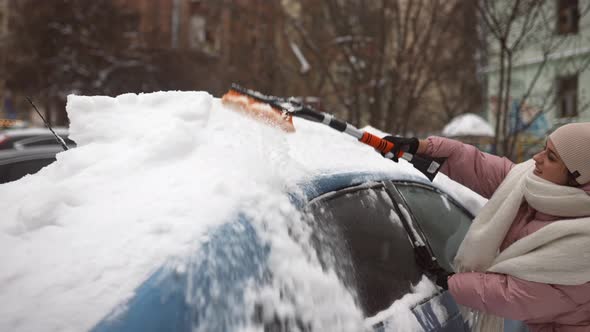 Woman Removing Snow From Car