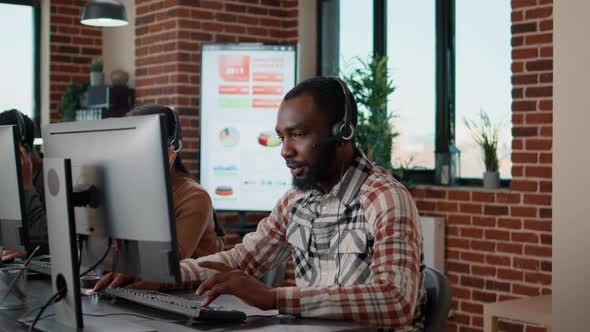 Young Man Using Headphones at Call Center to Help People