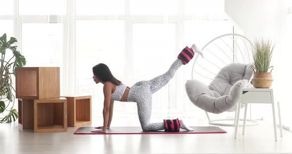 Fitness black woman in sportswear practicing exercise with ankle weight.