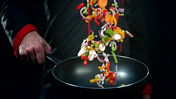 Super Slow Motion Shot of Chef Holding Frying Pan and Falling Vegetables at 1000Fps.