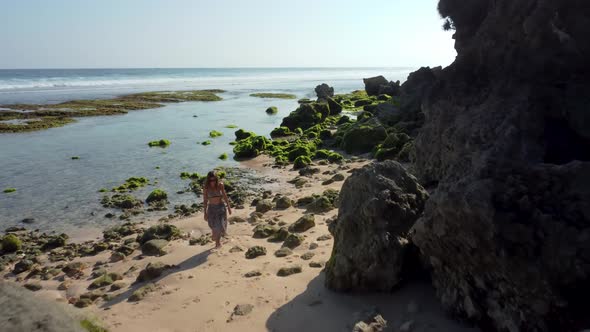 Woman Walks in the Beach Near to Rocks Seaweed