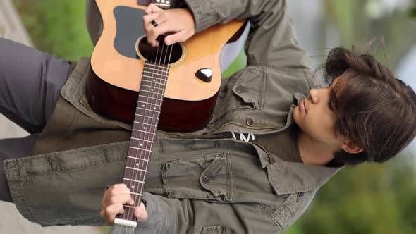 Teenage Boy Playing Guitar Outdoor in Park