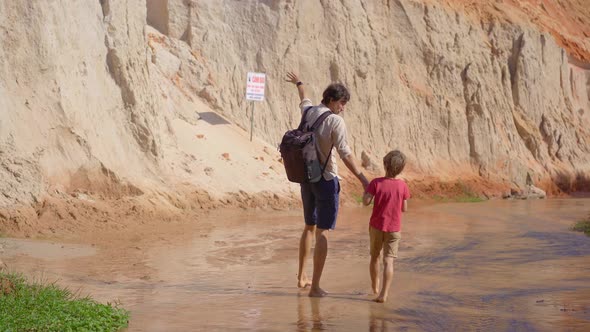 A Family Walks Along a Red Canyon or Fairy Stream at the Border of Desert in the Mui Ne Village in