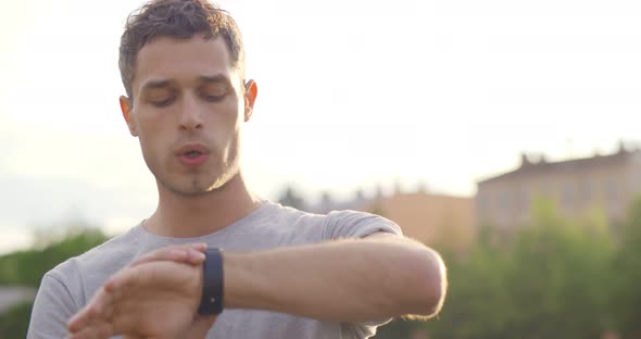 Young Caucasian Sportsman Checking Smartwatch App During Run at Park