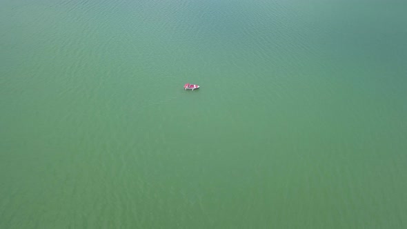 Aerial Approach shot of lake with boat floating in the middle, top down shot