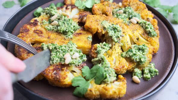 Eating grilled cauliflower steaks with homemade green pesto.