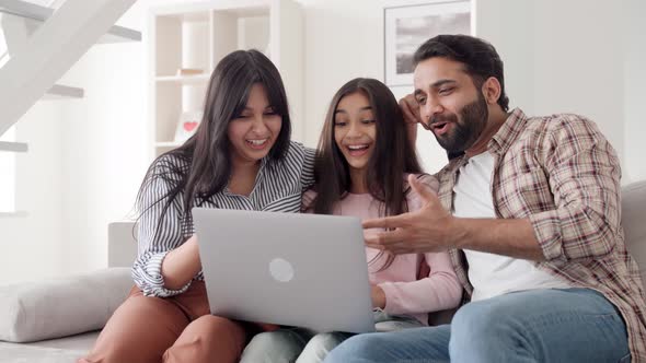 Happy Family Sits on Sofa at Home in Living Room with Laptop Watching Videos