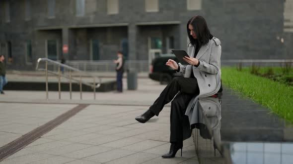 Successful Woman is Working with Tablet Outdoors in City Center