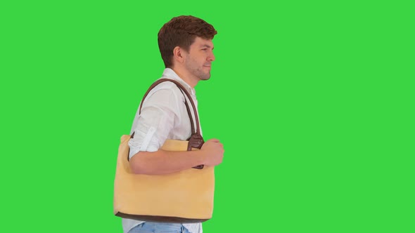 Handsome Smiling Man in White Shirt Walking with a Bag on His Shoulder on a Green Screen Chroma Key