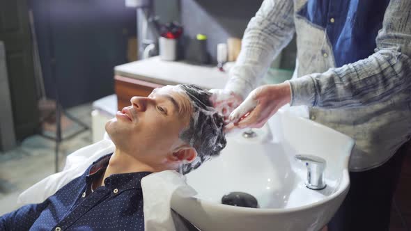 a Brunet Man Washes Hair with a Hairdresser in a Barbershop