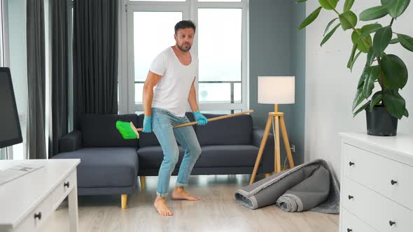 Man Cleaning the House and Having Fun Dancing with a Broom