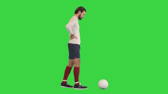Football Player Walking Slowly and Kicking the Ball on a Green Screen Chroma Key