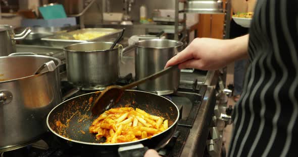 Stirring Penne Pasta With Sauce In A Skillet At The Restaurant Kitchen - close up, slow motion