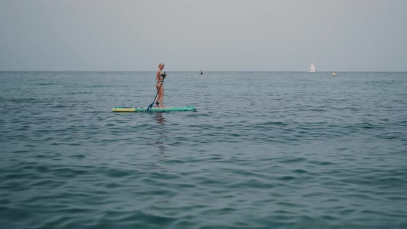 Woman in Bikini on Paddleboard in Sea
