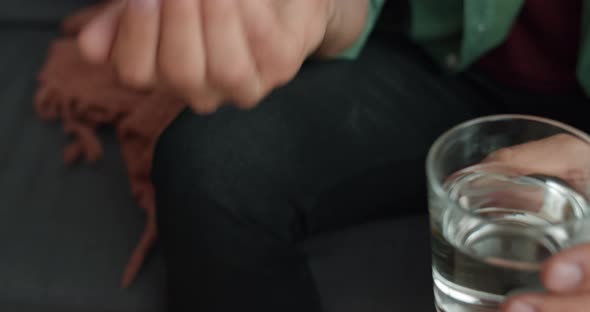 Crop View of Male Person Taking Two Pills and Drinking Them with Glass of Water. Concept of