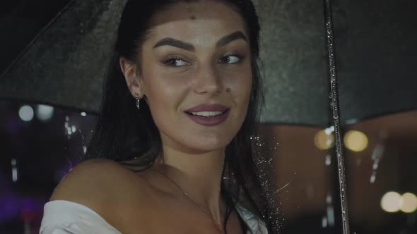 Happy Girl with Umbrella Rejoices at Camera Under Evening Summer Rain