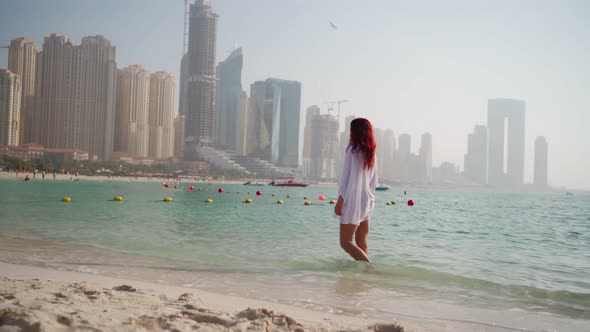 Woman in a White Shirt Walks Along the Beach of the Persian Gulf in Dubai