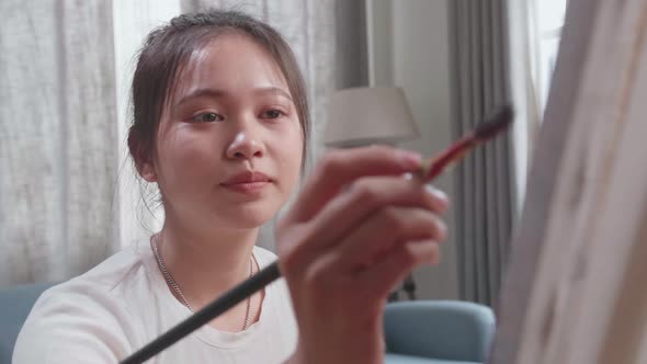 Close Up Of Asian Artist Girl Sitting And Holding Paintbrush And Thinking Before Painting