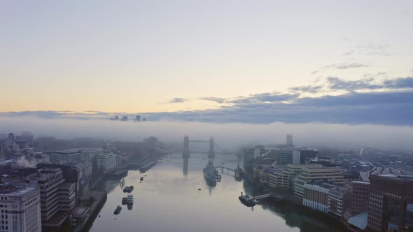 Fog over Tower Bridge London thames river at sunrise canary wharf in background